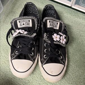 Converse black canvas sneakers with a double tongue and daisy flower charms.
